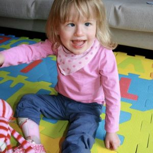 2 year old EJ sitting on a play mat, wearing pink and blue for undiagnosed children's day 2013